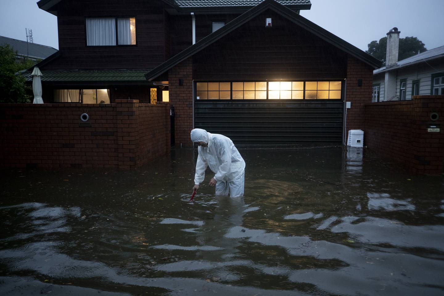 A man tries to clear the drain outside his house in Greenlane during the worst flooding the Auckland region has ever experienced. Photo / Dean Purcell