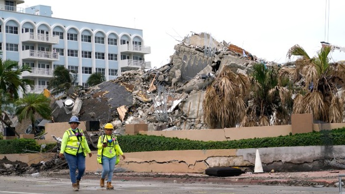 Workers walk past the collapsed and subsequently demolished Champlain Towers South condominium building. (Photo / AP)