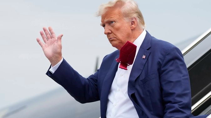 Former President Donald Trump steps off his plane as he heads to Washington to face a judge on federal conspiracy charges. Photo / AP