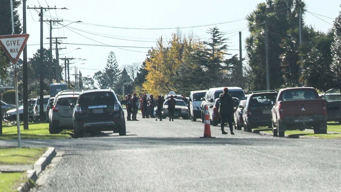 Gang members and vehicles line an Ōpōtiki street near an address where slain Mongrel Mob president Steven Rota Taiatini is believed to lie. Photo / NZME