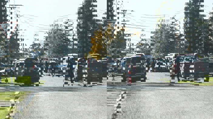 Gang members and vehicles line an Ōpōtiki street near an address where slain Mongrel Mob president Steven Rota Taiatini is believed to lie. Photo / NZME