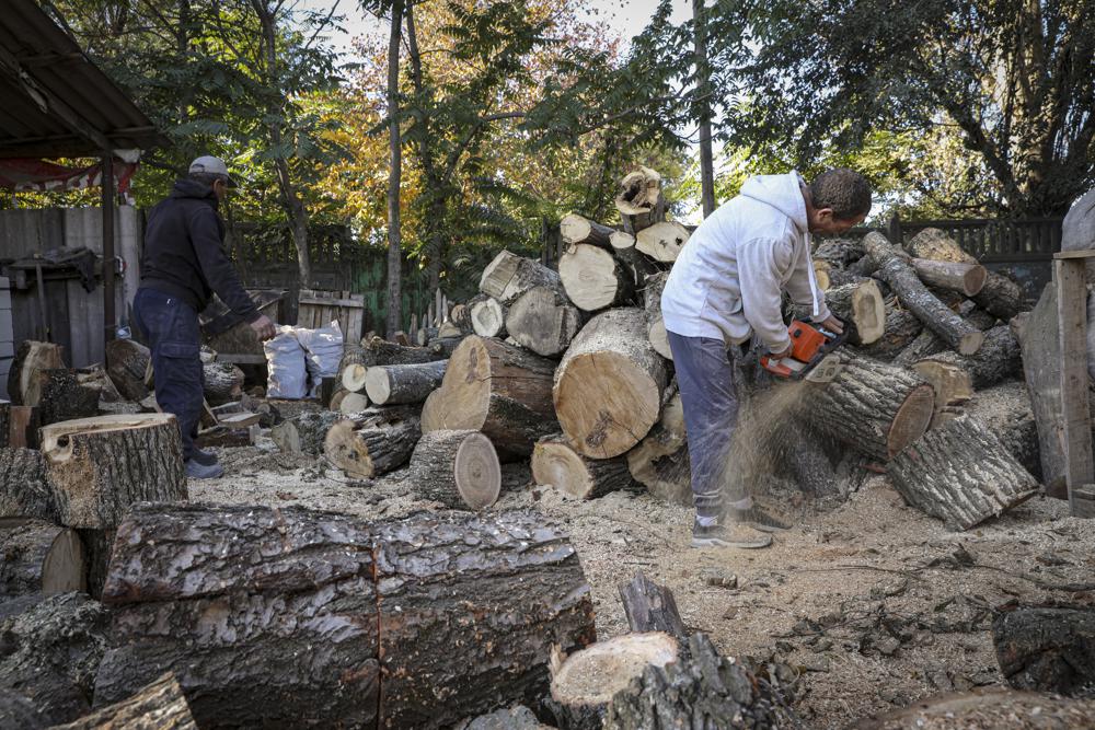 Men cut wood for heating outside Chisinau, Moldova, Saturday, Oct. 15, 2022. Europe's energy crisis, triggered by Russia slashing natural gas flows amid its war against Ukraine, has forced some people to turn to cheaper heating sources like firewood as the weather gets colder. But as more people stock up and burn wood, prices have skyrocketed, shortages and thefts have been reported, and scams are emerging. (AP Photo/Aurel Obreja)