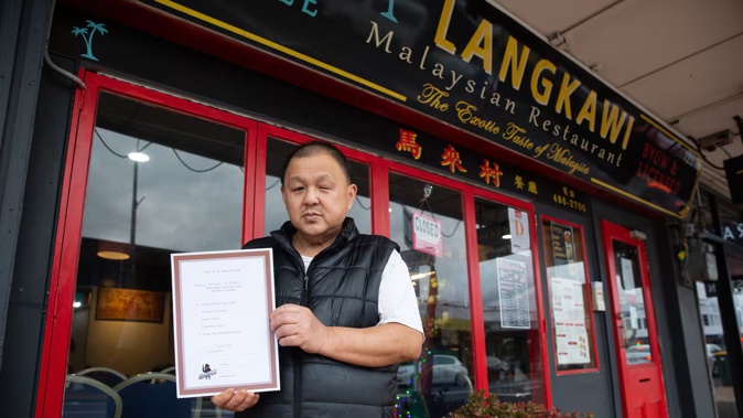 Henry Hew, owner of Langkawi Restaurant in Milford, holding a certificate showing he had pest control work carried out. Photo / Sylvie Whinray