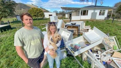 Mackenzie Wiig and fiancee Michaela Tait with Dexter and their Cyclone Gabrielle flood-damaged property in Esk Valley. They will not receive a full insurance payout for a property they cannot return to. Photo / Warren Buckland