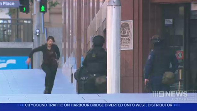 A woman escapes from the siege at the Lindt cafe (Channel 9 News)