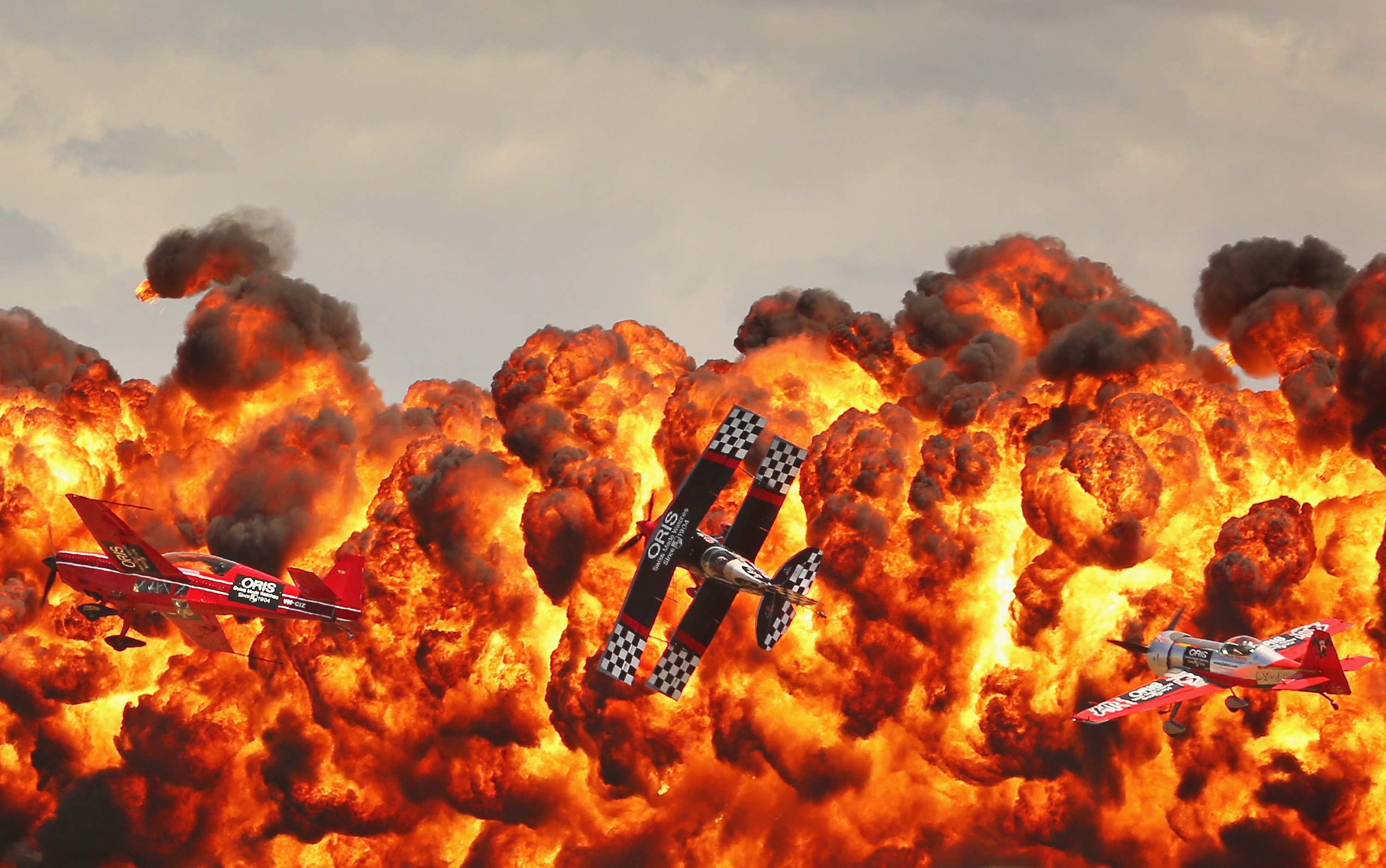 Stunt pilots Melissa Pemberton, Jurgis Kairys and Skip Stewart of The Immortals fly past pyrotechnics as they perform at The Australian International Airshow.