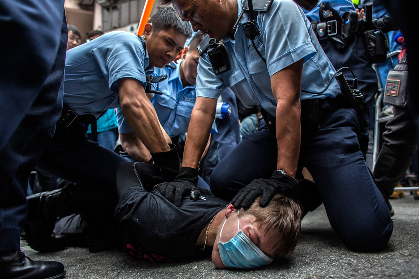 Police hold down a protester in Yuen Long during a rally against parallel-goods trading .