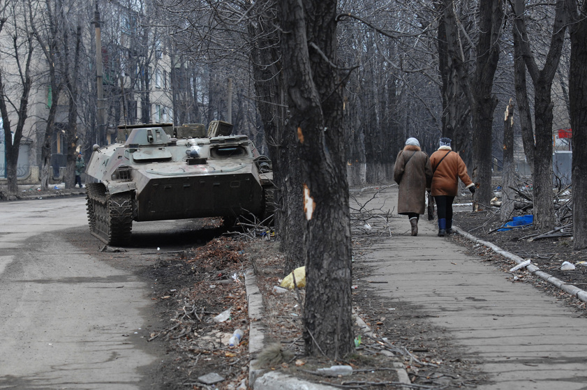 Two Ukrainian women walk past a wrecked armored personnel carrier as Debaltseve copes with the aftermath of a siege and then capture by Russian-backed separatists from the Ukrainian Army of Debaltseve, Ukraine, on March 3, 2015.