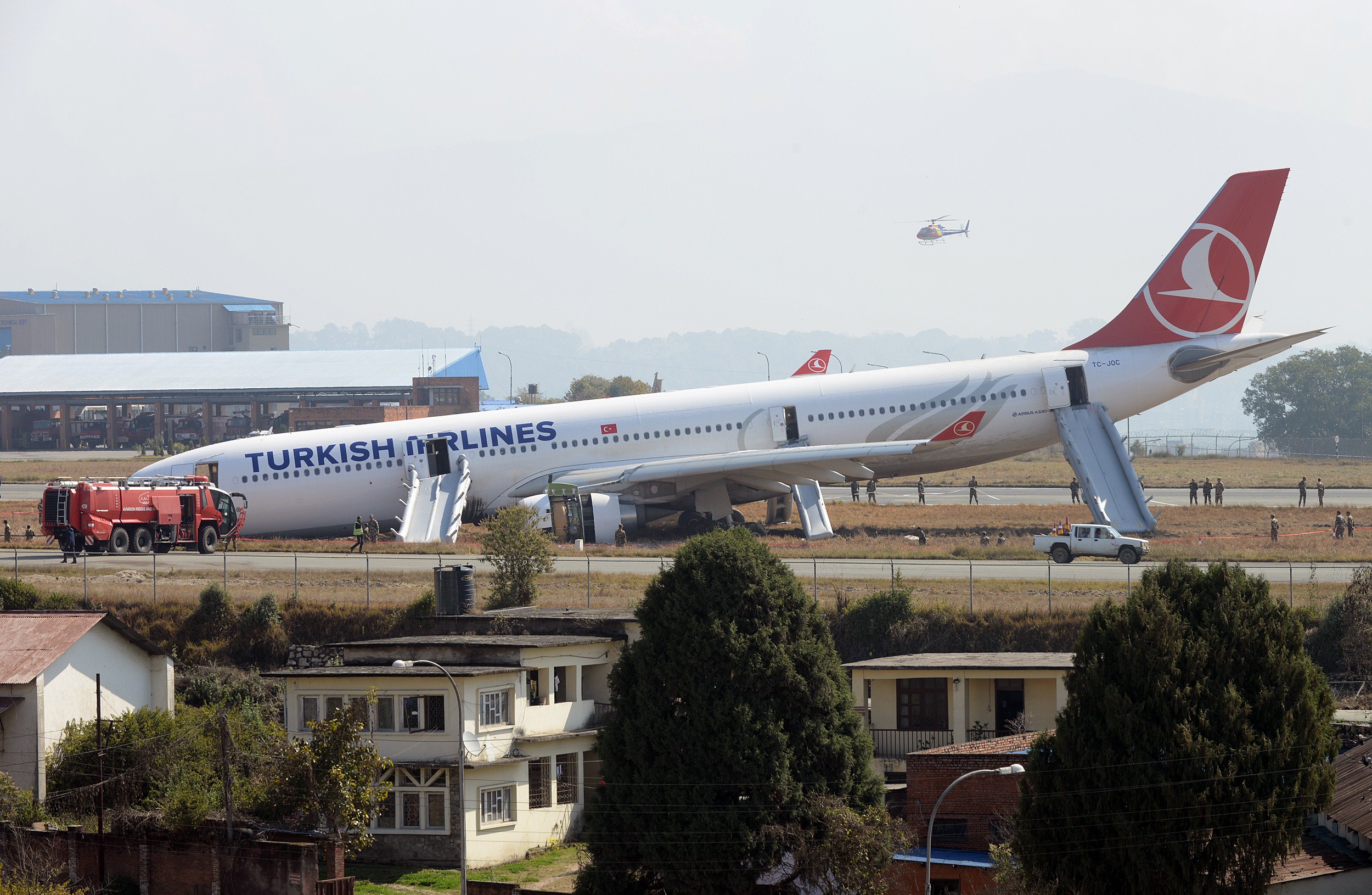 Rescue workers check the area around a Turkish Airlines plane after it slid off the tarmac at Kathmandu's international airport on March 4, 2015.