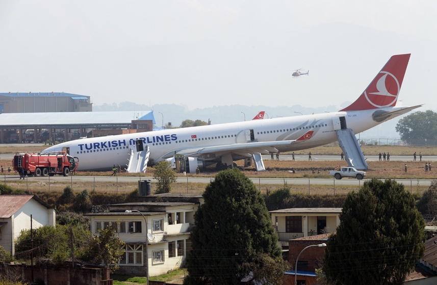 Rescue workers check the area around a Turkish Airlines plane after it slid off the tarmac at Kathmandu's international airport on March 4, 2015.