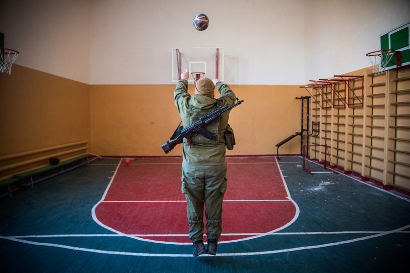 A Ukrainian soldier from the Azov Battalion plays basketball in a school gymnasium before being sent back to the front lines.