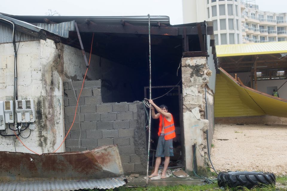 A man in Vanuatu tries to hold his roof up.