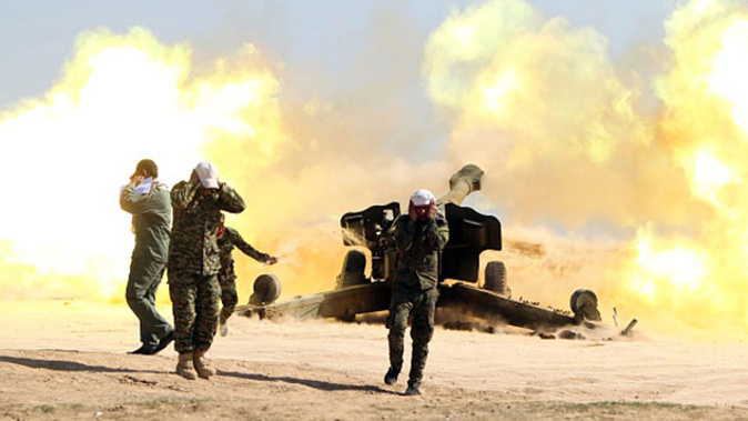 Volunteer Shiite fighters, known as the Popular Mobilisation units, who support the Iraqi government forces in the combat against the Islamic State (IS) group fire a Howitzer artillery canon in the village of Awaynat near the city of Tikrit (Getty Images) 
