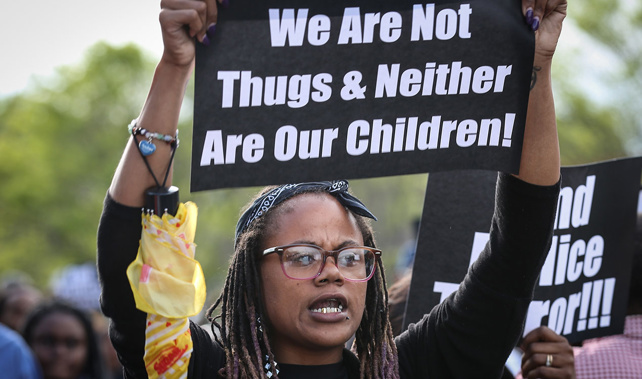 A protester holds a placard as she marches to the city hall, Baltimore (Getty Images)