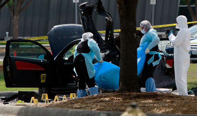 Investigators remove a body as they work a crime scene outside the Curtis Culwell Center (Getty Images)
