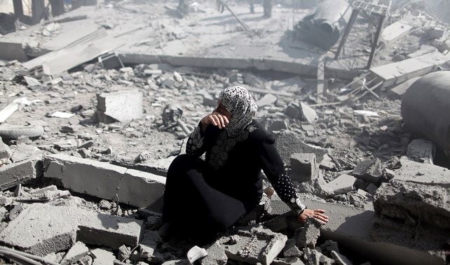 A Palestinian woman weeps amongst the debris of buildings as palestinian people walk around and inside the debris of the buildings, destroyed by Israeli fierce bombardments (Getty Images)