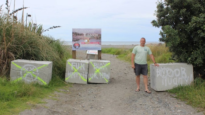 Brent Jarnell beside the concrete blocks preventing vehicle access to a small Te Horo Beach carpark. Photo / David Haxton