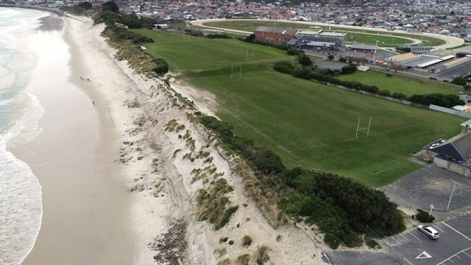 An aerial photograph shows the steep scarp, rocks and other rubble left behind after erosion at Ocean Beach, as well as the site of the old landfill buried under the Kettle Park playing fields behind the dunes. Photo / Otago Daily Times