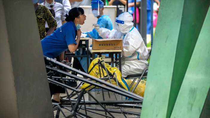A worker wearing a protective suit swabs a woman's throat for a COVID-19 test at a coronavirus testing site in Beijing, Wednesday, July 6, 2022. (Photo / AP)