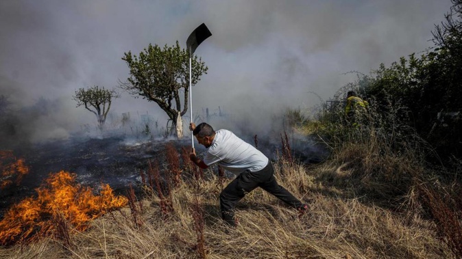 A local resident fights a forest fire with a shovel during a wildfire in Tabara, north-west Spain, July 19, 2022. Photo / AP