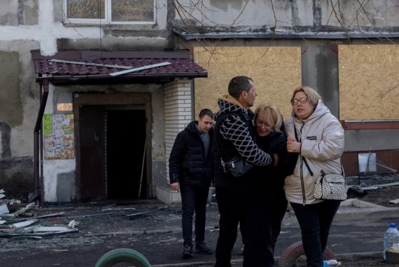 People hug a crying woman near a damaged residential building following a strike in Dobropillia in Ukraine, which killed 11 people and wounded 40. Photo / AFP