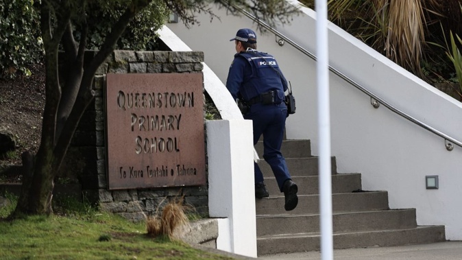 A policeman enters Queenstown Primary School after a number of threats were issued to schools across New Zealand today.
