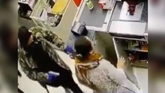 Kingston Gough points the gun near the head of Flagstaff Superette co-owner Rafia Farooqi. Photo / Supplied