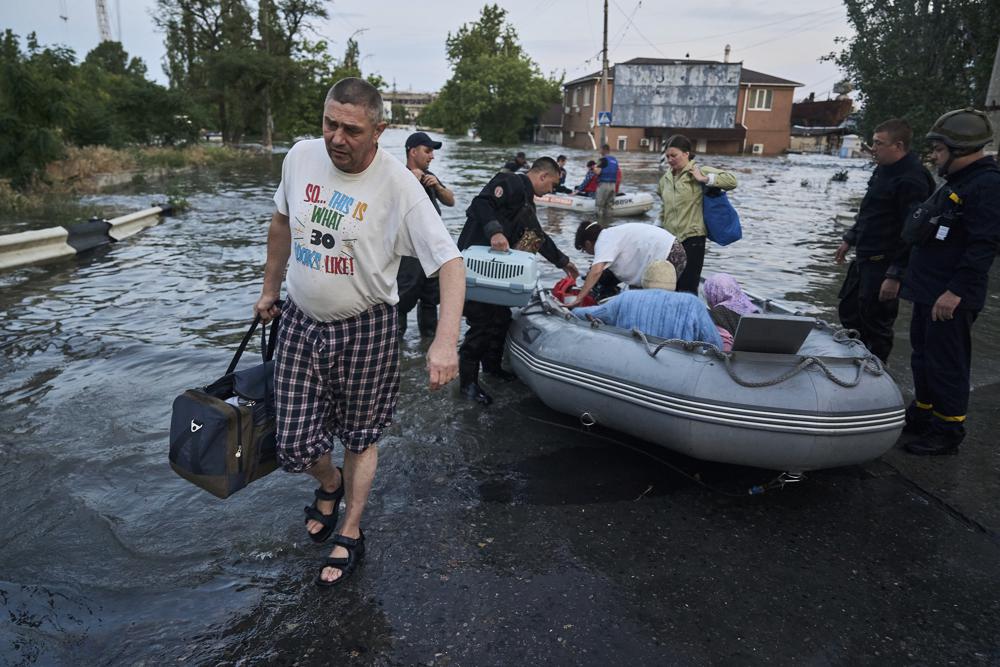 Rescue workers attempt to tow boats carrying residents being evacuated from a flooded neighborhood in Kherson, Ukraine. (AP Photo/Libkos)