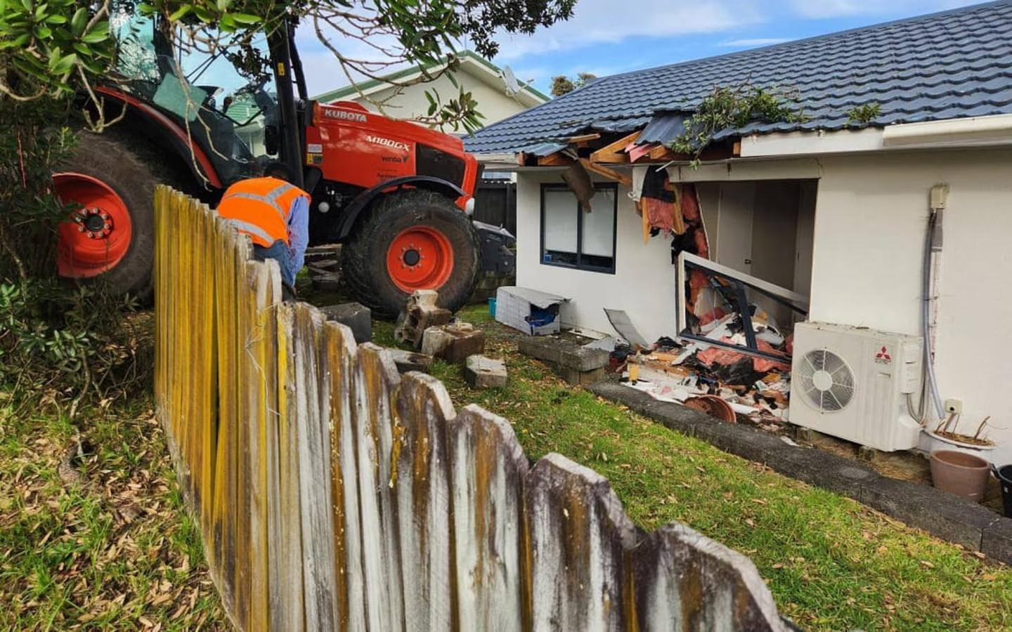 A house on Glenfield Road, North Shore, Auckland, was left with a hole in the roof and smashed section of wall when a tractor crashed into it. Photo: RNZ / Finn Blackwell