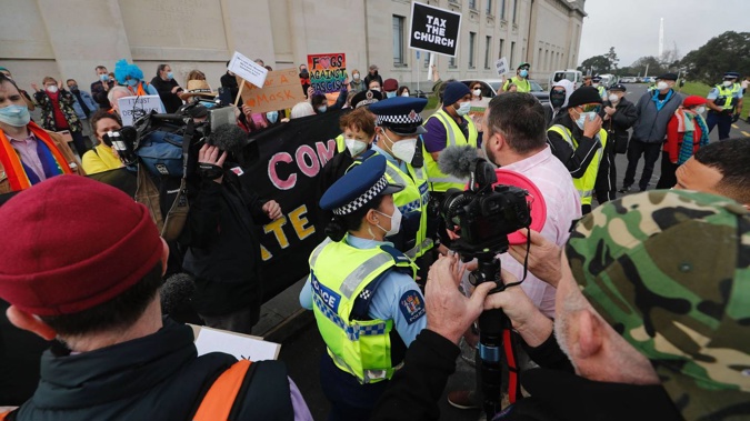 A pro-Freedom & Rights Coalition supporter was blocked by police in getting close to the counter-protest group at the Domain. (Photo / Dean Purcell)