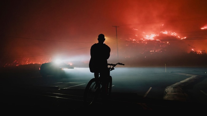 There are fears of a difficult summer ahead for California after the traumatic wildfires that killed 30 people in January. A pedestrian records the Palisade fire in Los Angeles on January 7. Photo / Philip Cheung, the New York Times