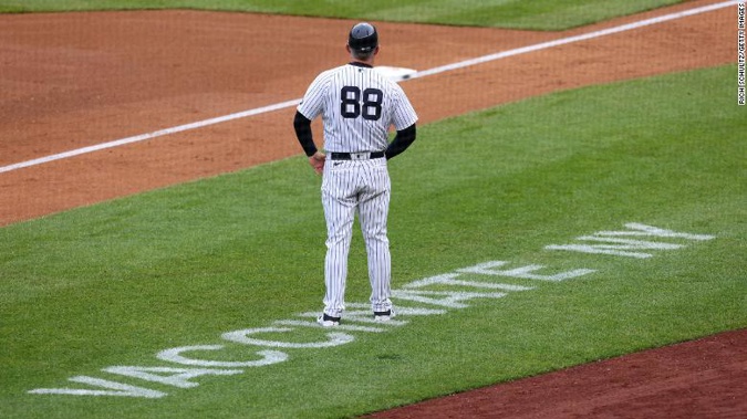 Third base coach Phil Nevin of the New York Yankees stood Saturday near the coaching box, atop a "Vaccinate NY" message painted on the field at Yankee Stadium. (Photo / CNN)