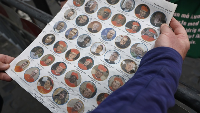 An Irish priest holds an Irish newspaper displaying photos of Cardinals who could become the next Pope outside the Vatican before a College of Cardinals' meeting on May 06, 2025 in Rome, Italy. (Photo by Mario Tama/Getty Images)