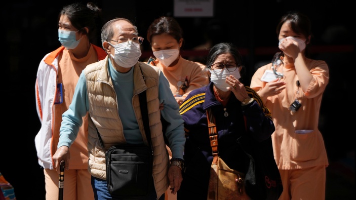 Elderly couple and medical staff walk out from the Queen Elizabeth Hospital in Hong Kong, Wednesday, March 9, 2022. (Photo / AP)