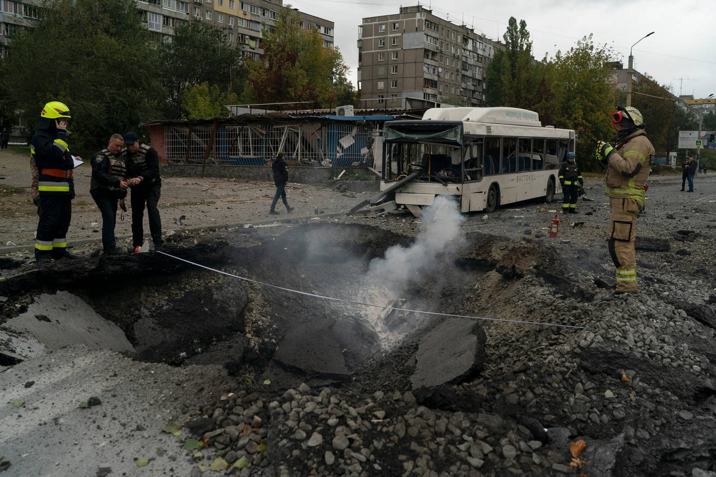 Firefighters and police officers work on a site where an explosion created a crater on the street after a Russian attack in Dnipro. Photo / Leo Correa, AP