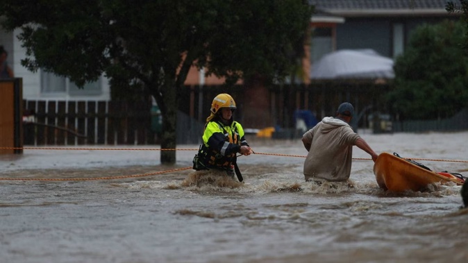 Firefighters use ropes to help rescue residents trapped by flooding Urlich Dr, Ranui. Photo / Hayden Woodward