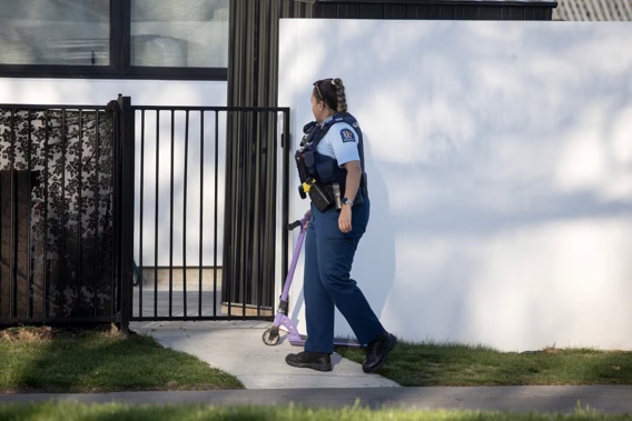 A policewoman passes a child's scooter at a property on Barrington St in Spreydon, Christchurch, where a child died on Wednesday. Photo / George Heard