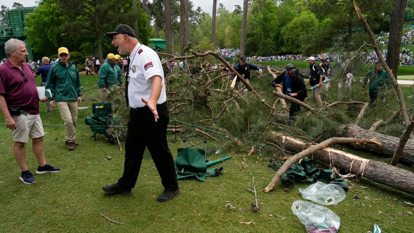 A security guard moves patrons away from trees that blew over on the 17th hole at Augusta National. Photo / AP