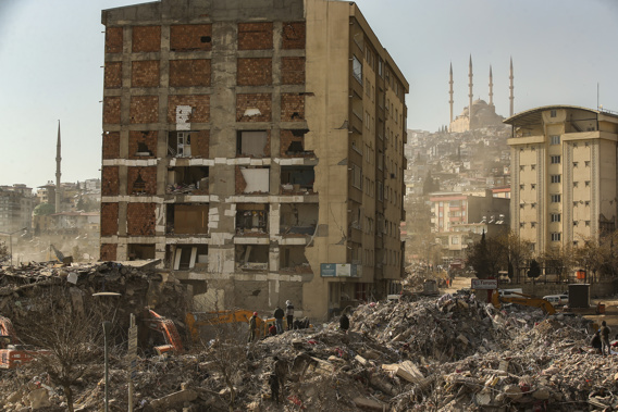 People stand by a collapsed building in Kahramanmaras, southern Turkey, Sunday, Feb. 12, 2023. Six days after earthquakes in Syria and Turkey killed tens of thousands, sorrow and disbelief are turning to anger and tension over a sense that there has been an ineffective, unfair and disproportionate response to the historic disaster. Photo / AP