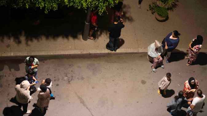 People take shelter and check for news on their mobile phones after an earthquake in Rabat, Morocco. Photo / AP