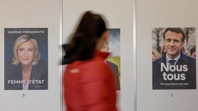 A voter walks past election posters of Marine Le Pen and Emmanuel Macron as polls for the first round of the French elections close. (Photo / AP)