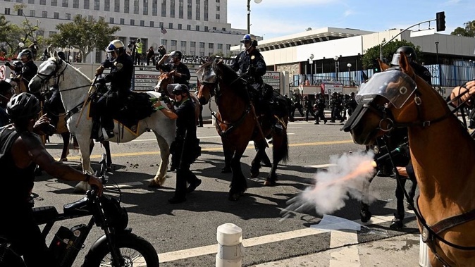 Police on horseback fire tear gas and rubber bullets to drive protesters back during the 'No Kings' day anti-Trump protest in Los Angeles yesterday, which followed previous protests against federal immigration raids. Photo / Keith Birmingham, MediaNews Group, Pasadena Star-News via Getty Images