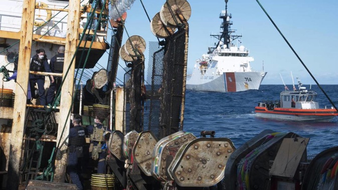 Guardsmen from the cutter James, seen at background right, conduct a boarding of a fishing vessel in the eastern Pacific Ocean. Photo / AP