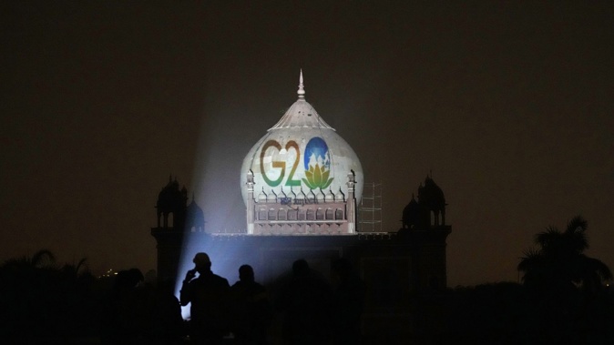 Archaeological Survey of India workers project the logo of G20 onto Safdarjung's tomb, in New Delhi. Photo / AP