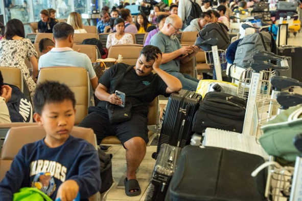 Passengers seated at Suvarnabhumi Airport, Thailand, with piles of luggage as a global IT disruption has affected retail, travel and other services. Photo / Getty Images