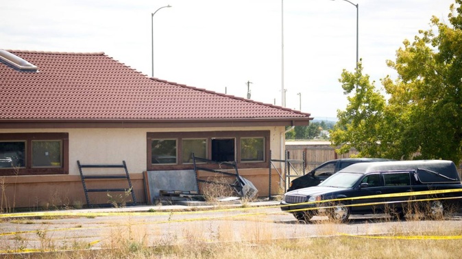 A hearse and van sit outside a closed funeral home where 115 bodies are being stored. Photo / AP