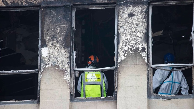 Police and fire investigators on the top level of Loafers Lodge as they search the site of the deadly arson attack. Photo / George Heard