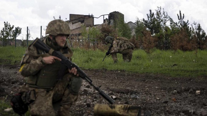 Ukrainian servicemen squat during a patrol in a recently retaken village, north of Kharkiv. Photo / AP