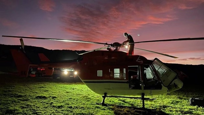 A member of the flight crew carries out checks on a helicopter at dawn today as firefighting efforts retart near Cape Rēinga. Photo / FENZ