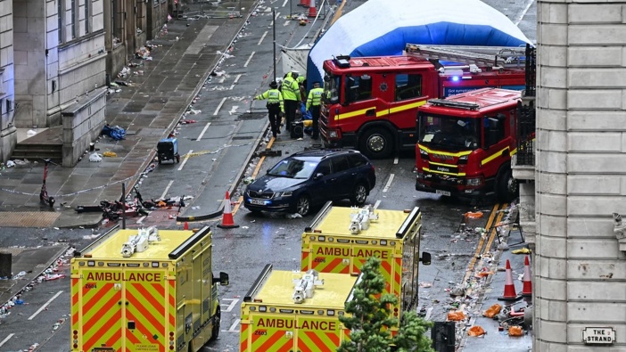Police officers cover with an inflatable tent, behind a firefighter vehicle, the tents delimiting the scene of an incident in Water St. Photo / AFP